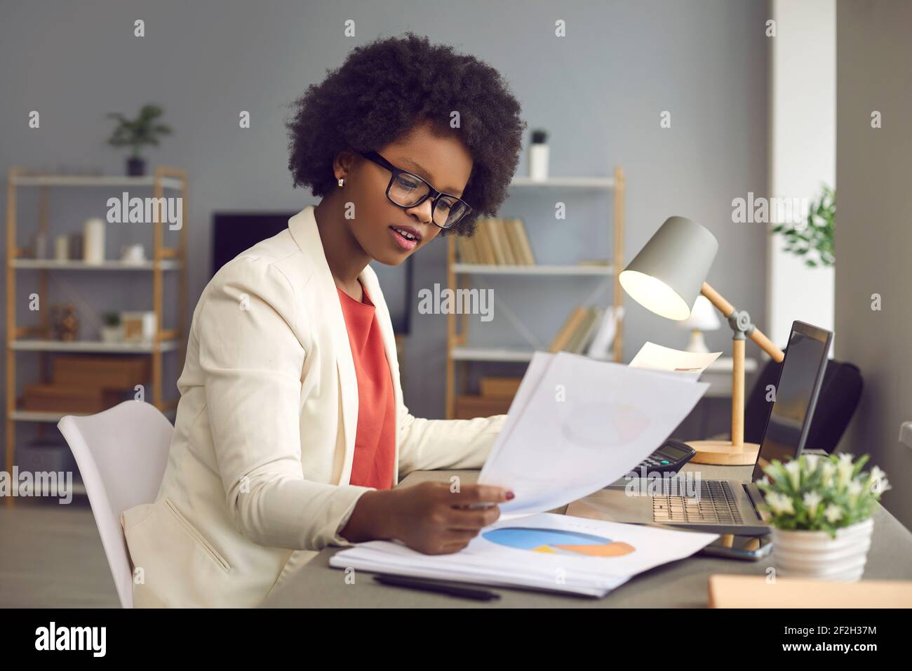African american businesswoman working with documents and laptop at office desk Stock Photo