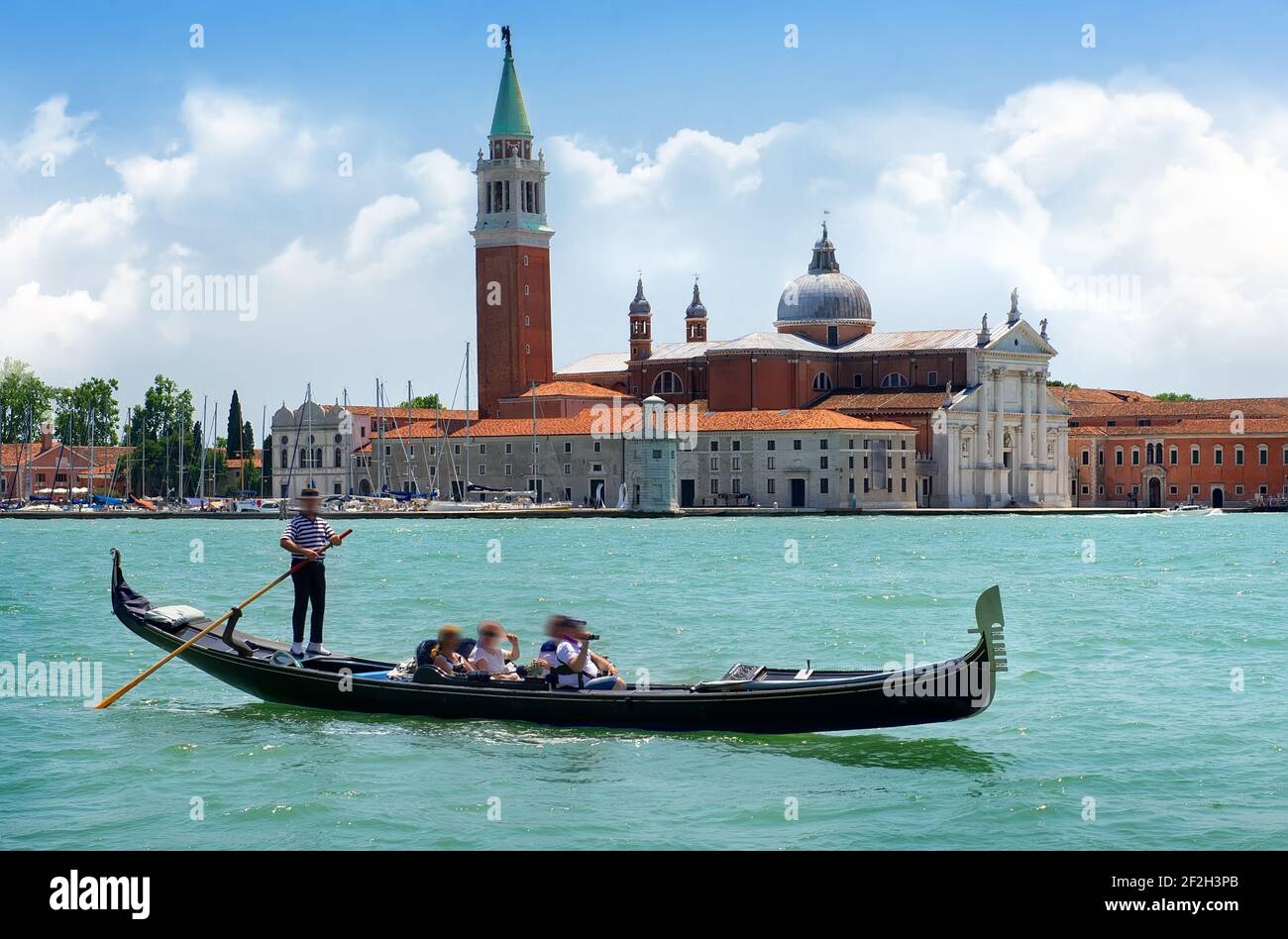 Tourists riding in gondola on Grand canal near San Giorgio Maggiore in Venice, Italy Stock Photo