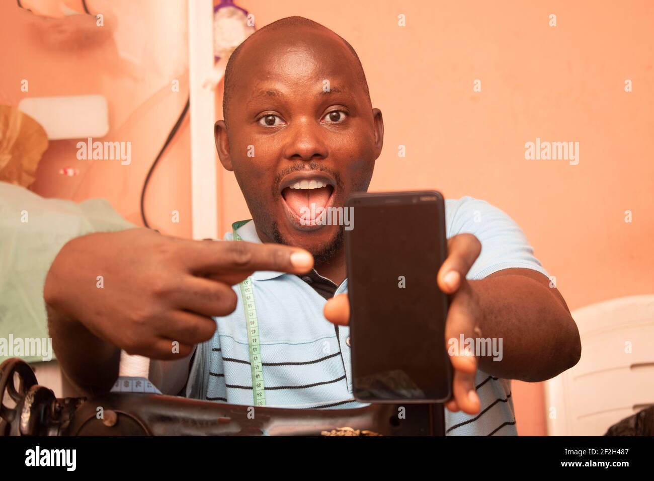 a tailor pointing to his mobile phone Stock Photo