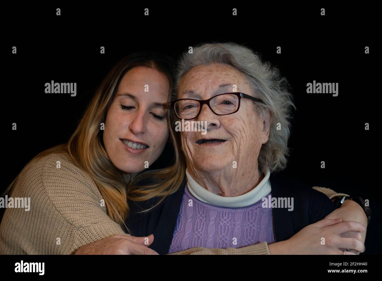 Family lifestyle portrait of elderly 80s woman hugging young grand daughter Stock Photo