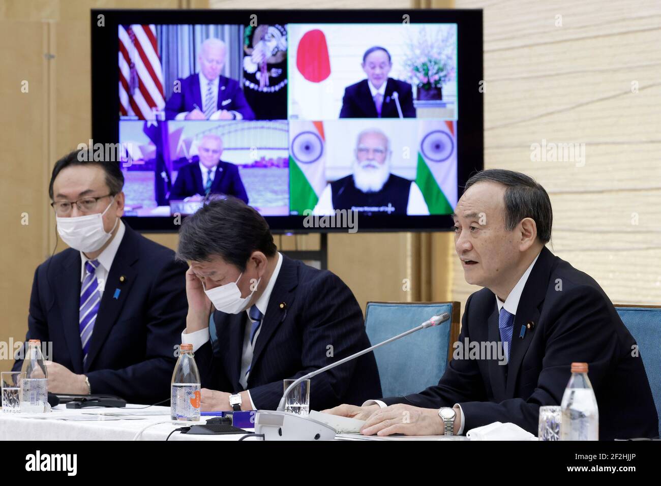 Tokyo, Japan. 12th Mar, 2021. Yoshihide Suga (R) Japanese Prime Minister speaks while a monitor displays U.S. President Joe Biden, Scott Morrison, Australia's Prime Minister, and Narendra Modi, India's Prime Minister, during the Virtual Quadrilateral Security Dialogue (Quad) meeting at his official residence in Tokyo, Japan, on Friday, March 12, 2021. Credit: POOL/ZUMA Wire/Alamy Live News Stock Photo