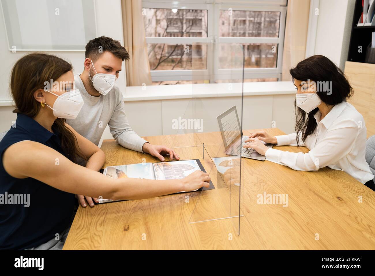 Young Couple With Travel Agent Wearing Face Mask Stock Photo
