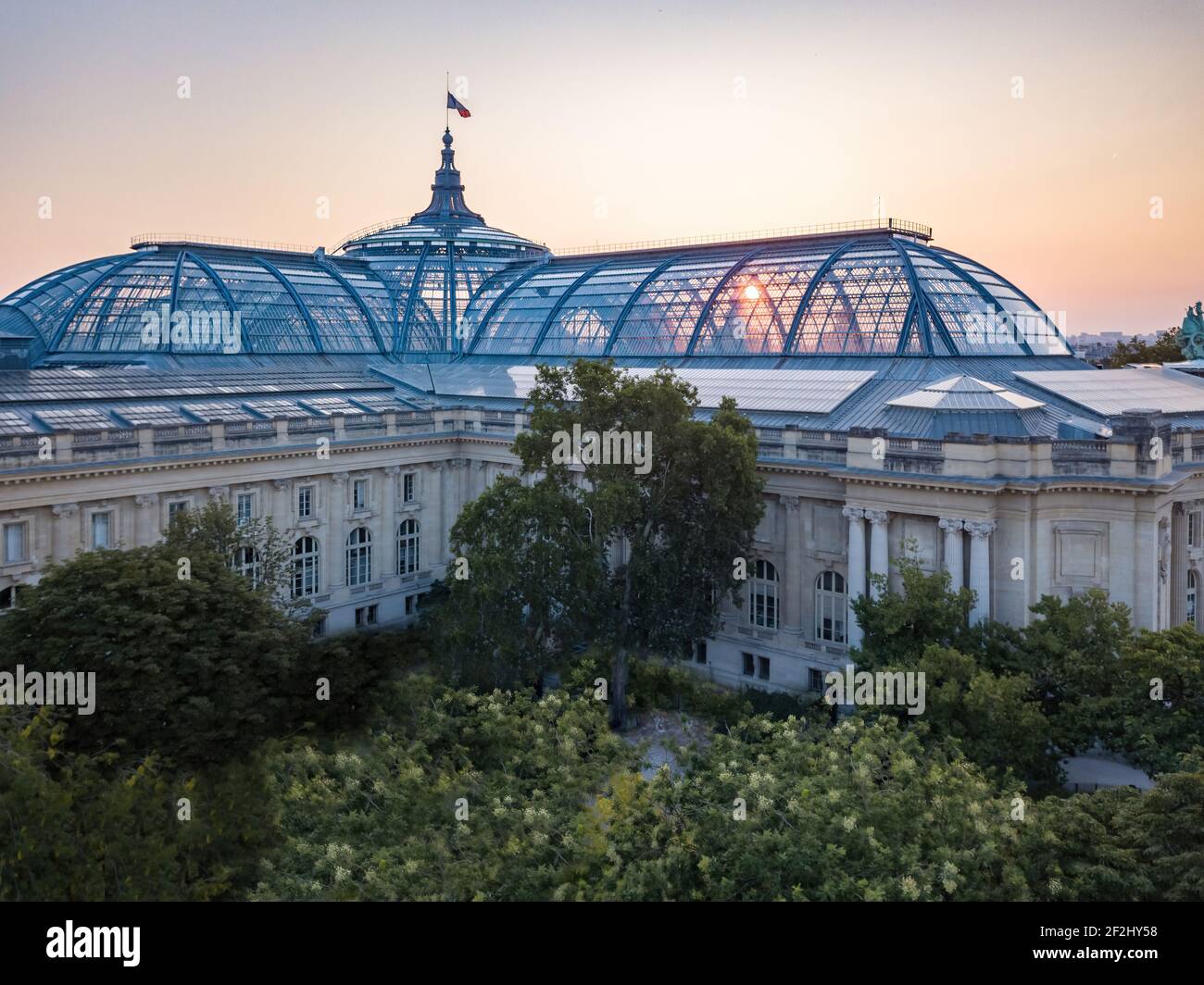 Aerial Sunrise through glass roof and Dome of the Grand Palais of Beaux Arts Architecture (Champs Élysées) in Paris, topped by the French flag Stock Photo