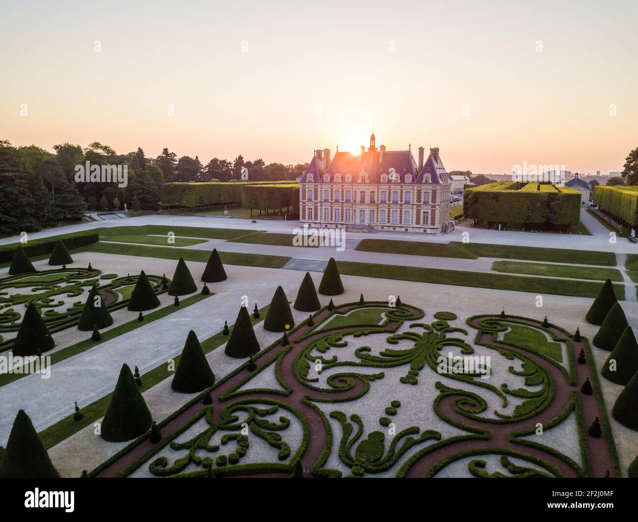 Aerial Sunset glare through chateau de Sceaux (Ile-de-France State Museum of local history) with Topiary in foreground Sceaux, Hauts-de-Seine. Stock Photo