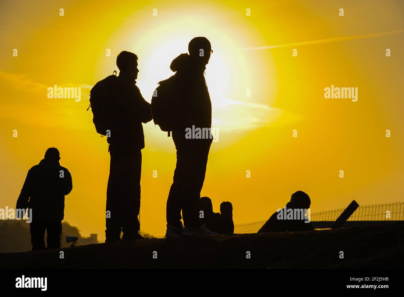 Spectators at a racing circuit at dawn silhouetted by the rising golden sun Stock Photo