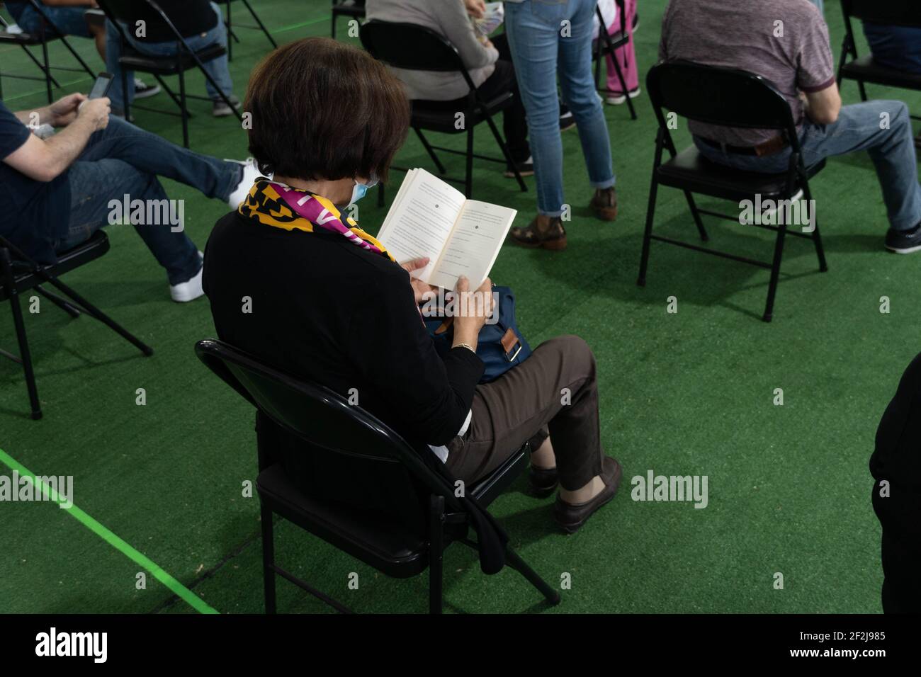 Santiago, Metropolitana, Chile. 12th Mar, 2021. A woman vaccinated with the Sinovac vaccine reads a book in the waiting room, where patients must wait 30 minutes after being vaccinated. Credit: Matias Basualdo/ZUMA Wire/Alamy Live News Stock Photo
