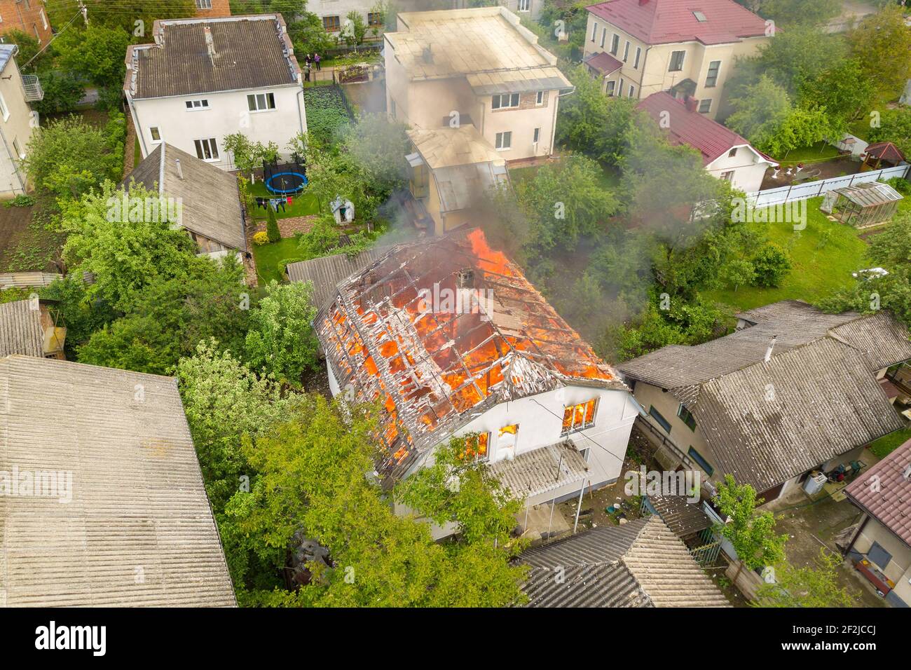 Aerial view of a house on fire with orange flames and white thick smoke ...