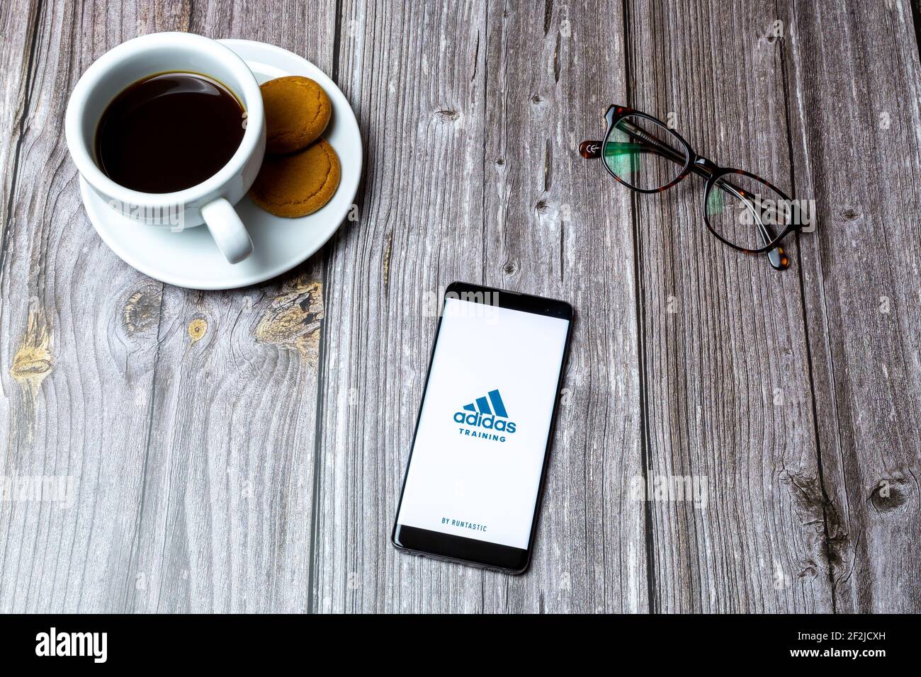 A Mobile phone or cell phone laid on a wooden table with the Adidas Training app open on screen Stock Photo