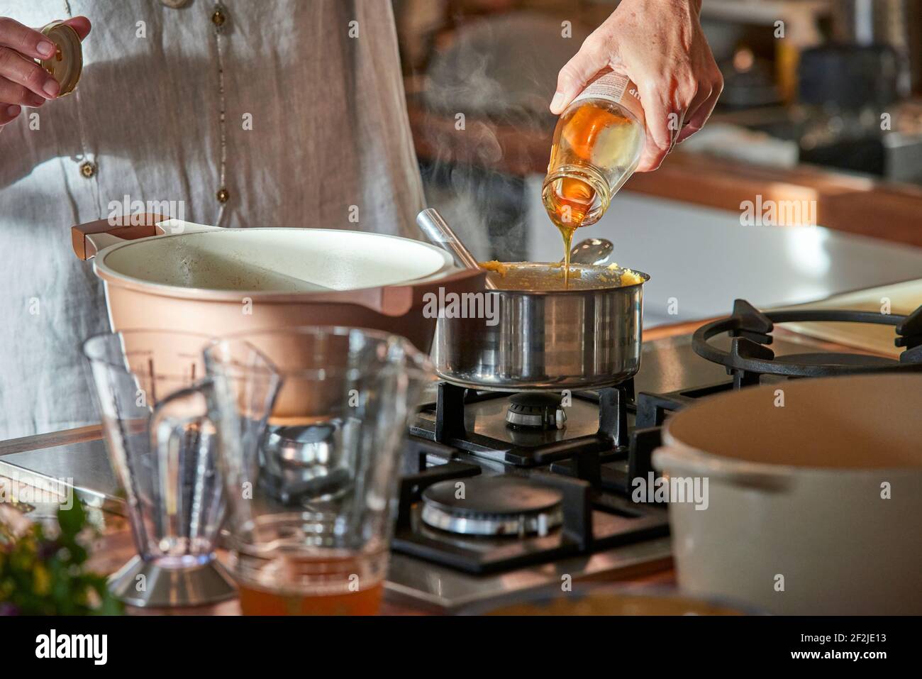 Woman's hand pours coconut syrup from a glass bottle into a stick cassar roll Stock Photo