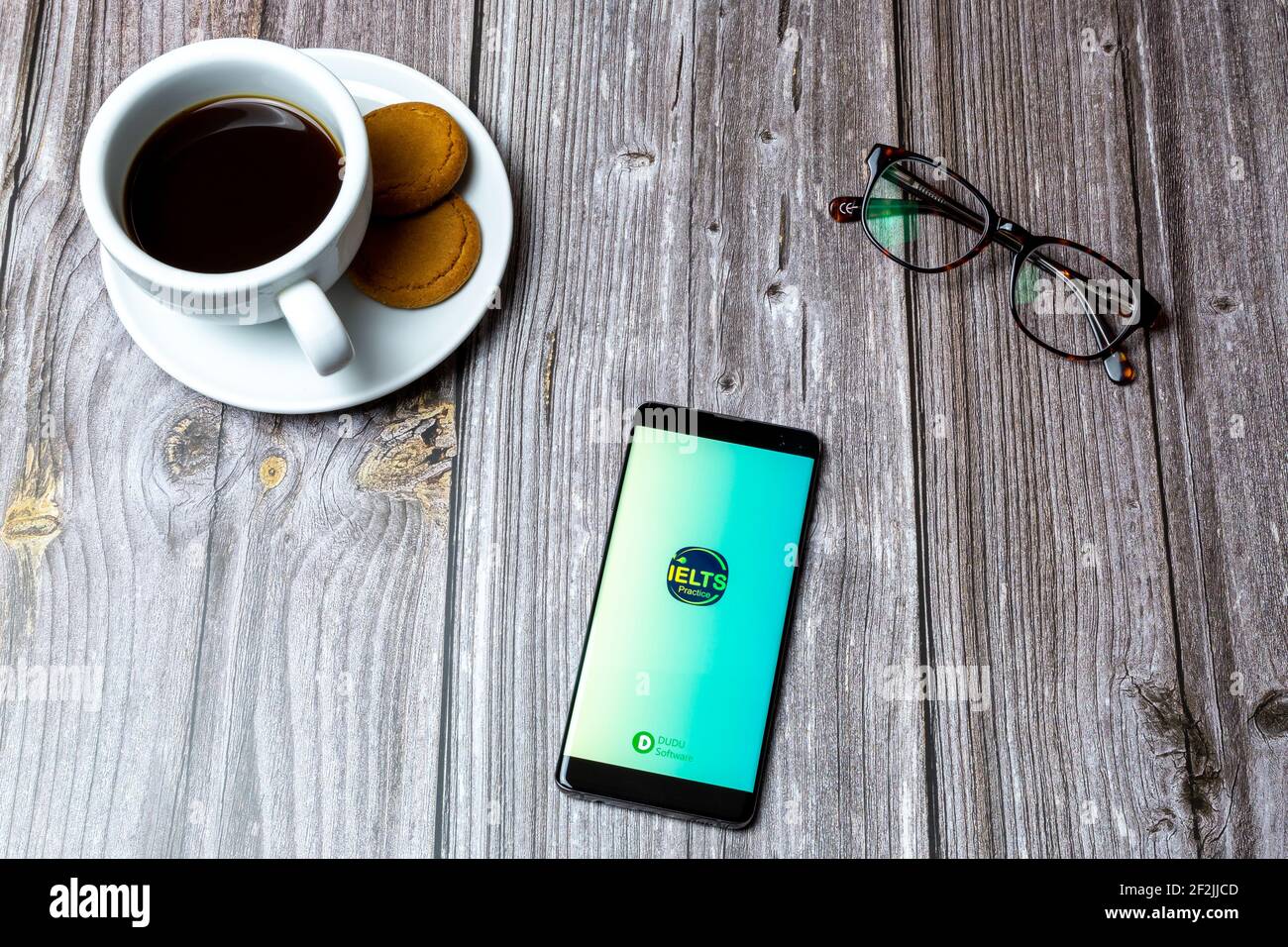 A Mobile phone or cell phone laid on a wooden table with the IELTS Practice app open on screen Stock Photo