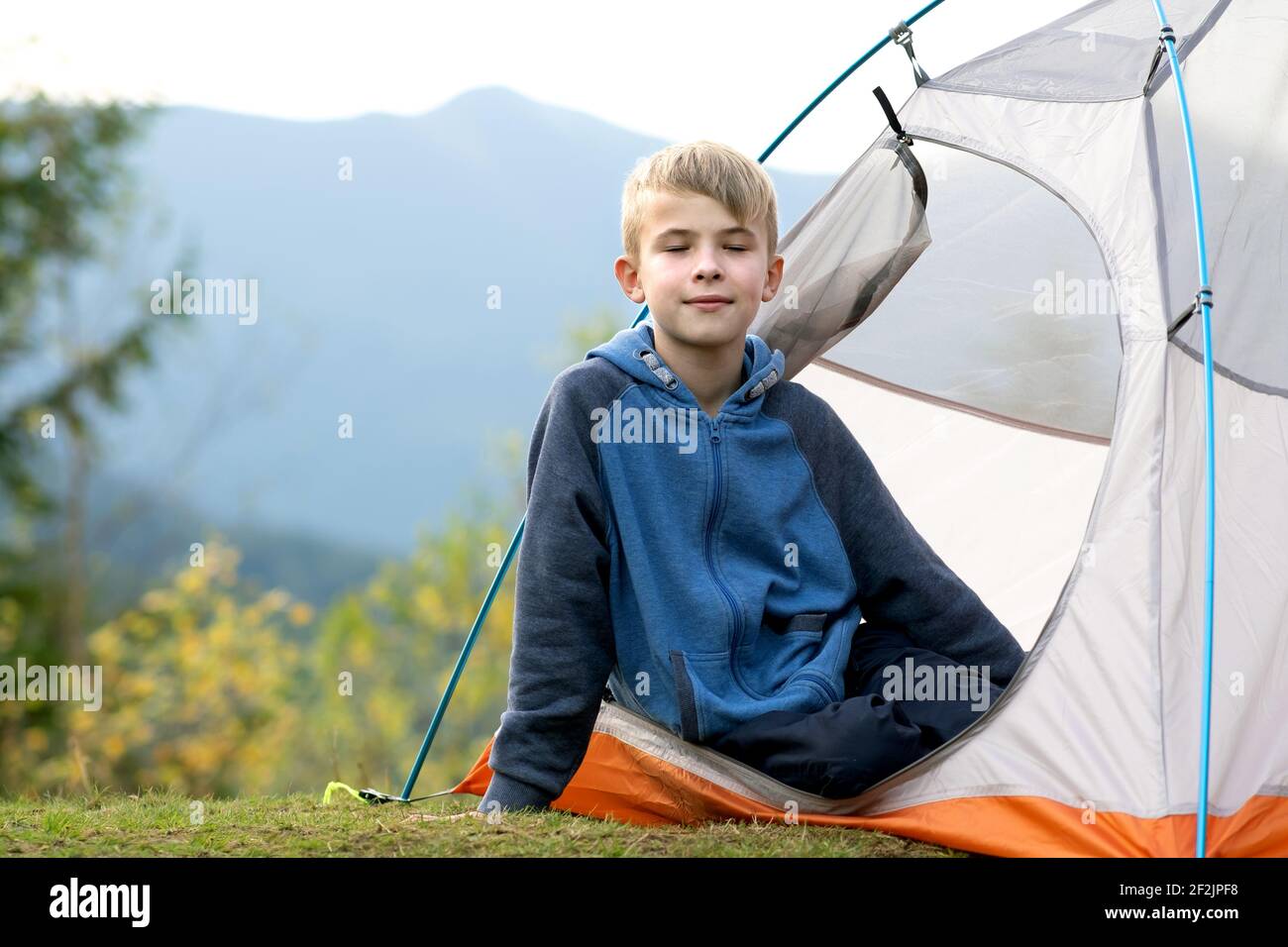 Happy hiker child boy resting in a tourist tent at mountain campsite ...