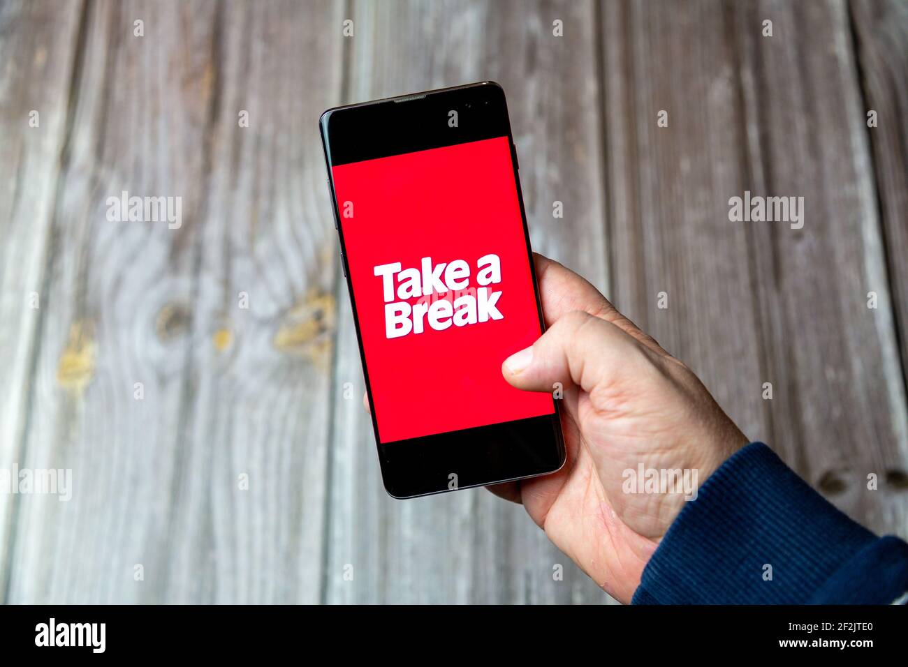 A Mobile phone or cell phone being held in a hand with the Take a Break app open on screen Stock Photo