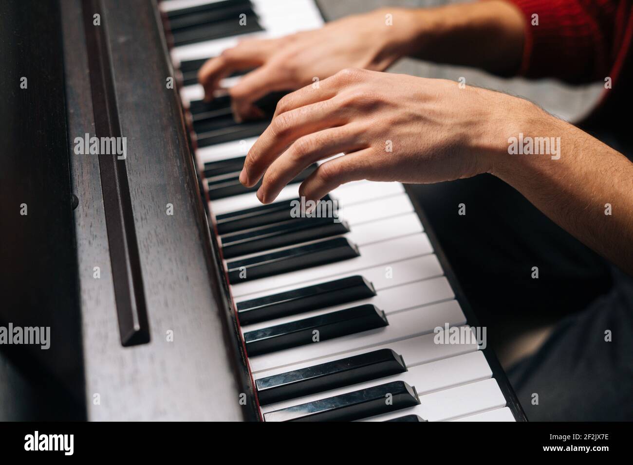 Closeup hands of unrecognizable man playing on piano at home recording