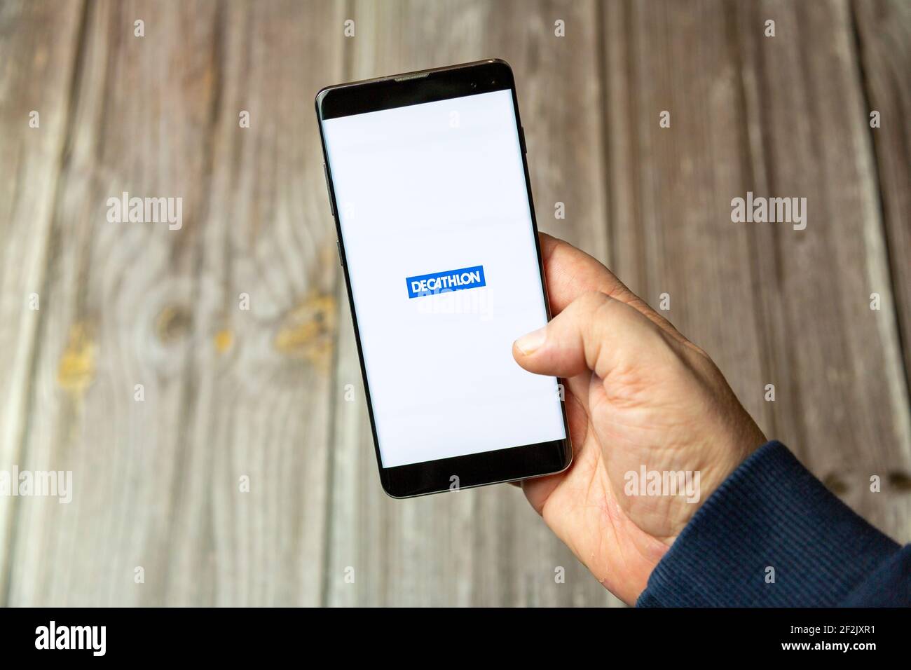 A Mobile phone or cell phone being held in a hand with the Decathlon app  open on screen Stock Photo - Alamy