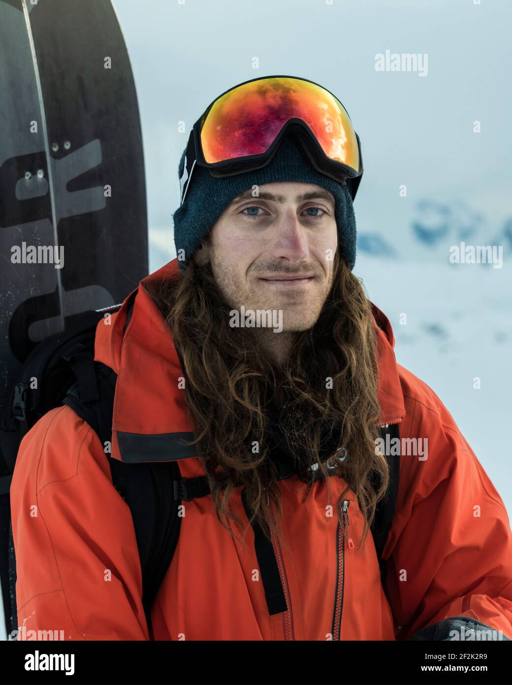 Portrait of mid adult man in warm clothing carrying snowboard Stock Photo