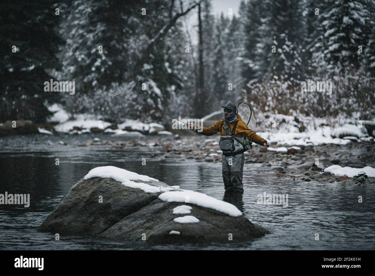 Man fly fishing while standing in river during winter Stock Photo