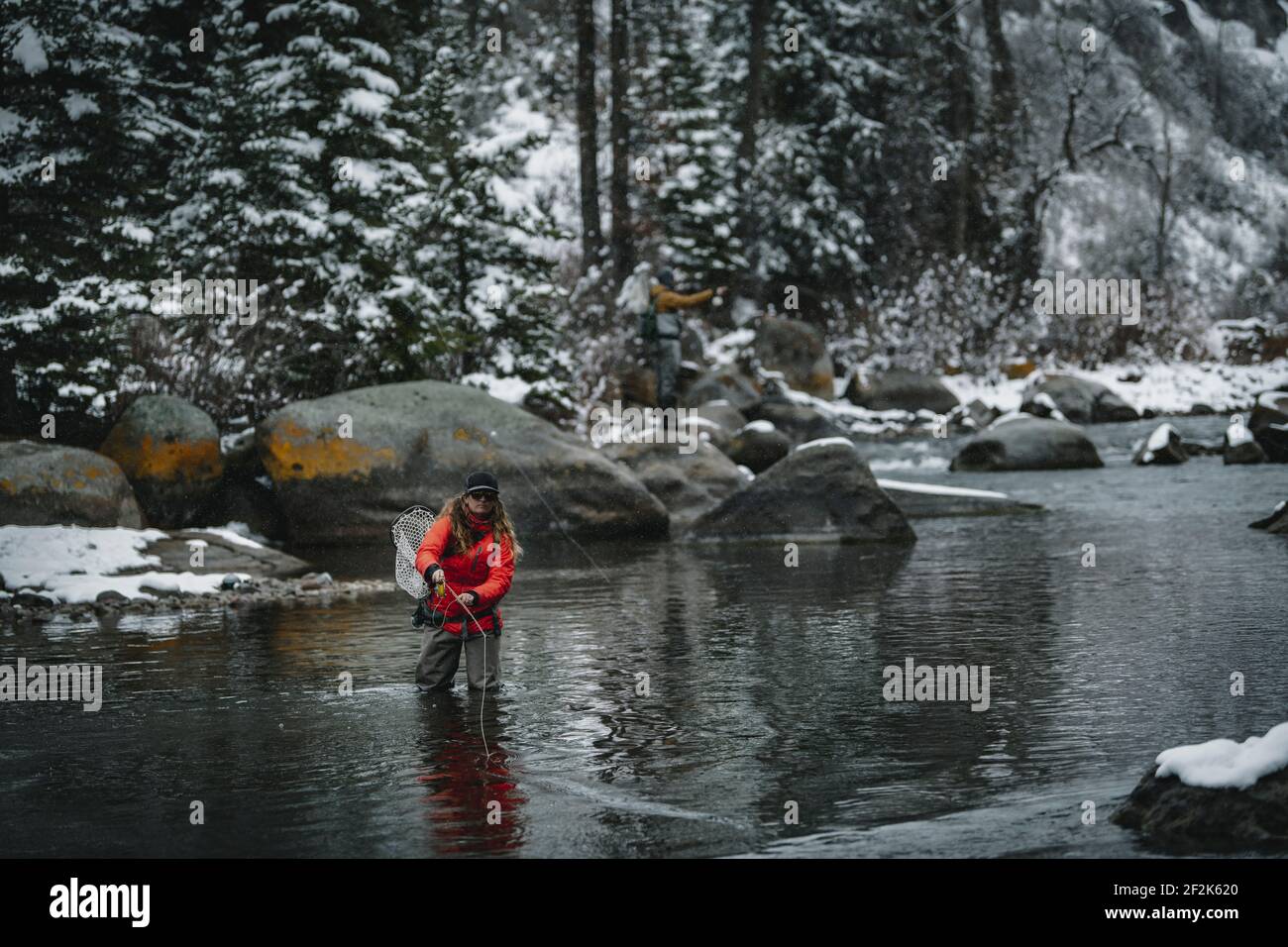 Woman fly fishing while standing in river during winter Stock Photo