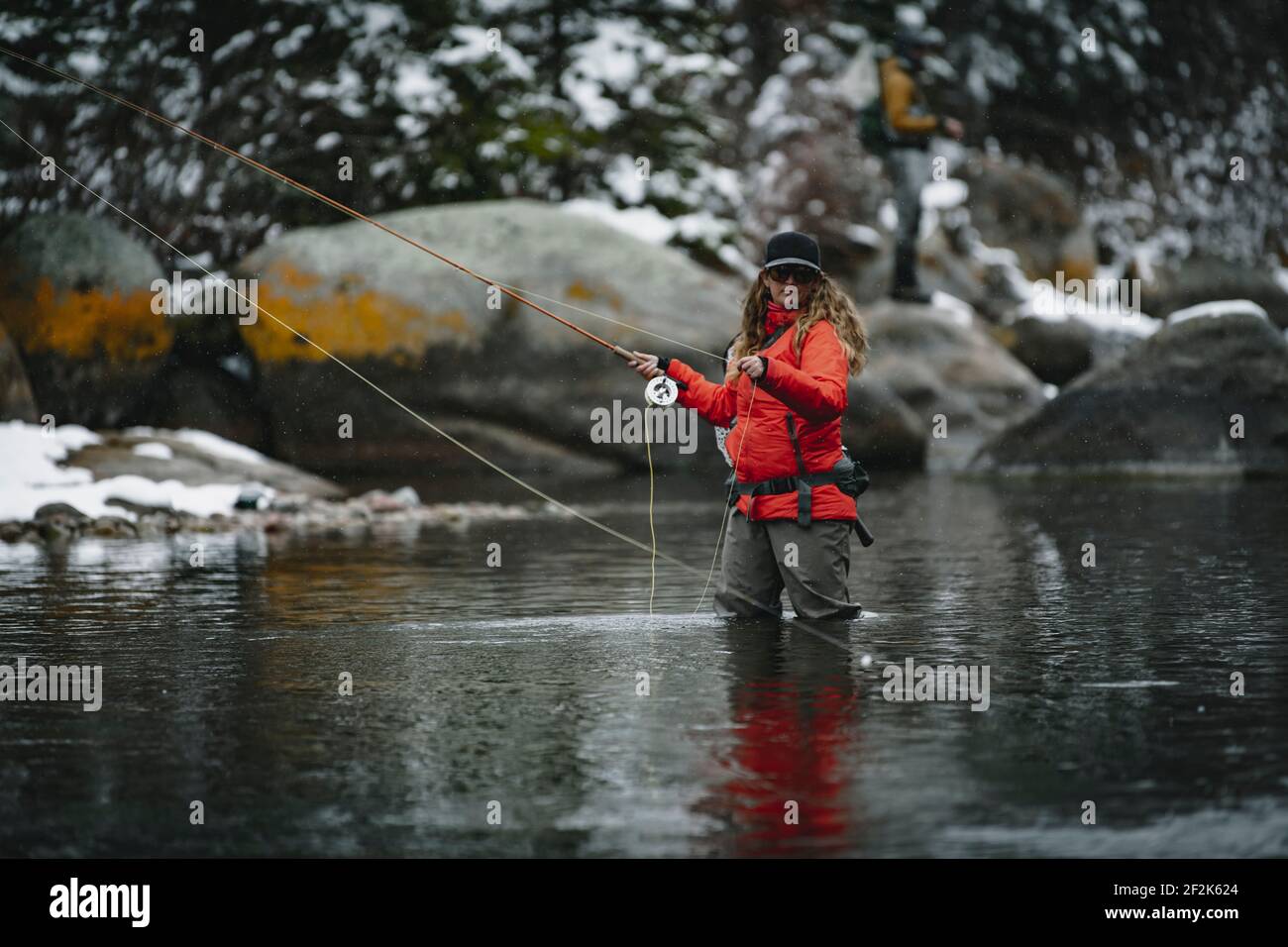 Woman fly fishing while standing in river during winter Stock Photo