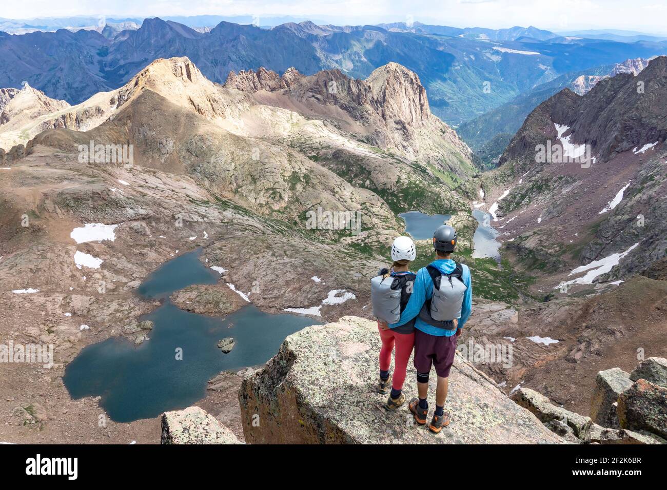 Rear view of couple looking at view while standing on mountain Stock Photo