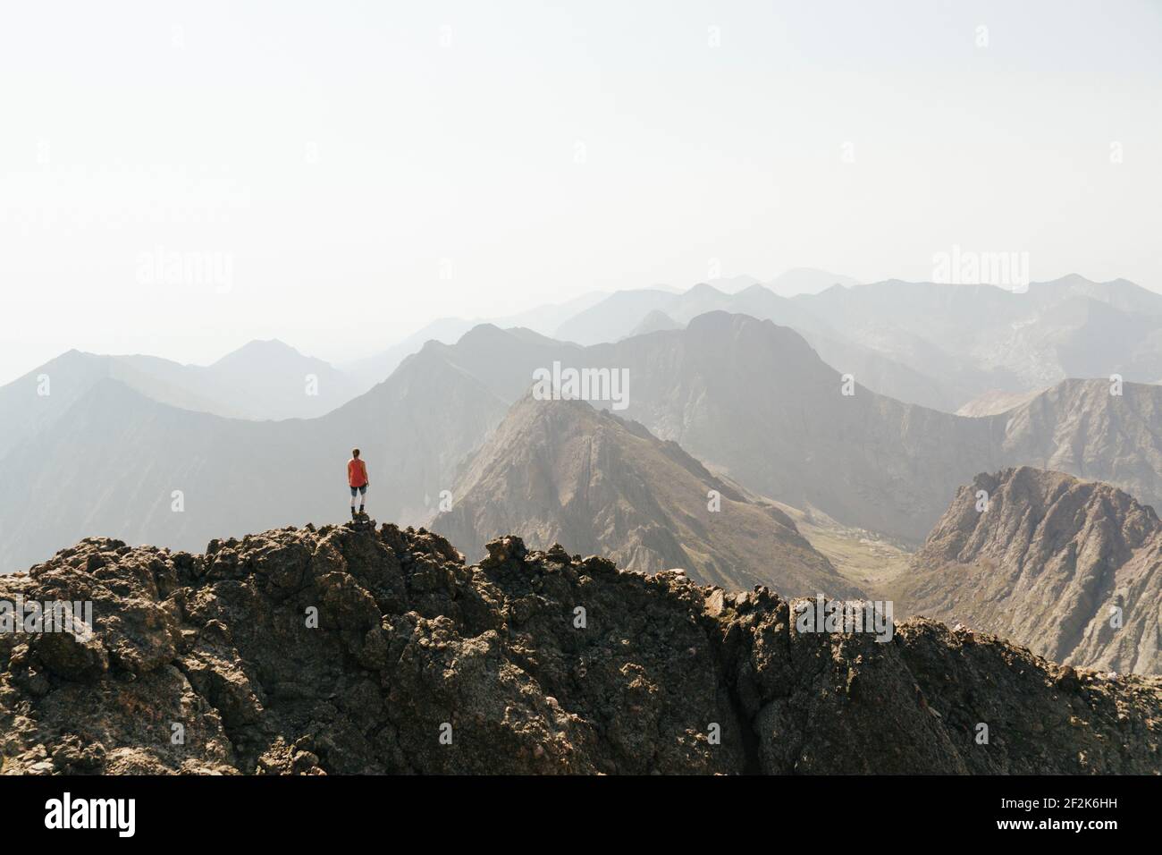 Woman looking at view while standing on peak of mountain against clear sky Stock Photo