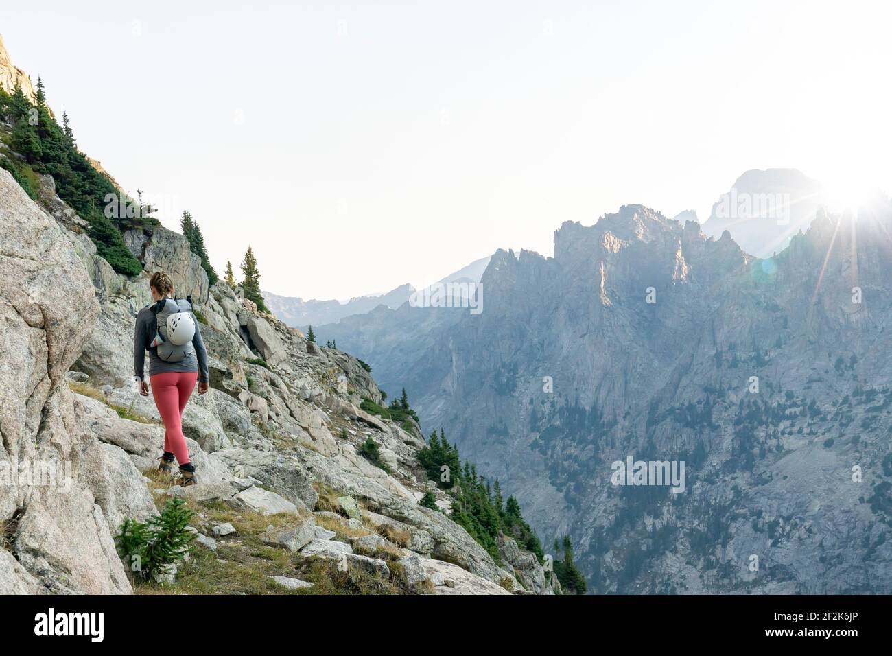 Rear view of woman hiking on mountain against clear sky during vacation Stock Photo