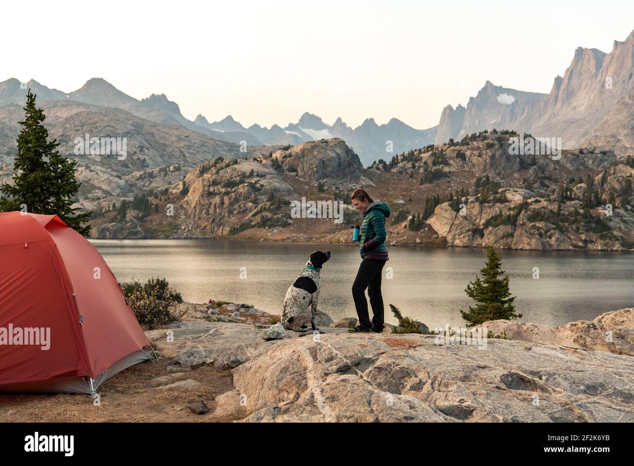 Side view of woman camping with dog by during vacation Stock Photo