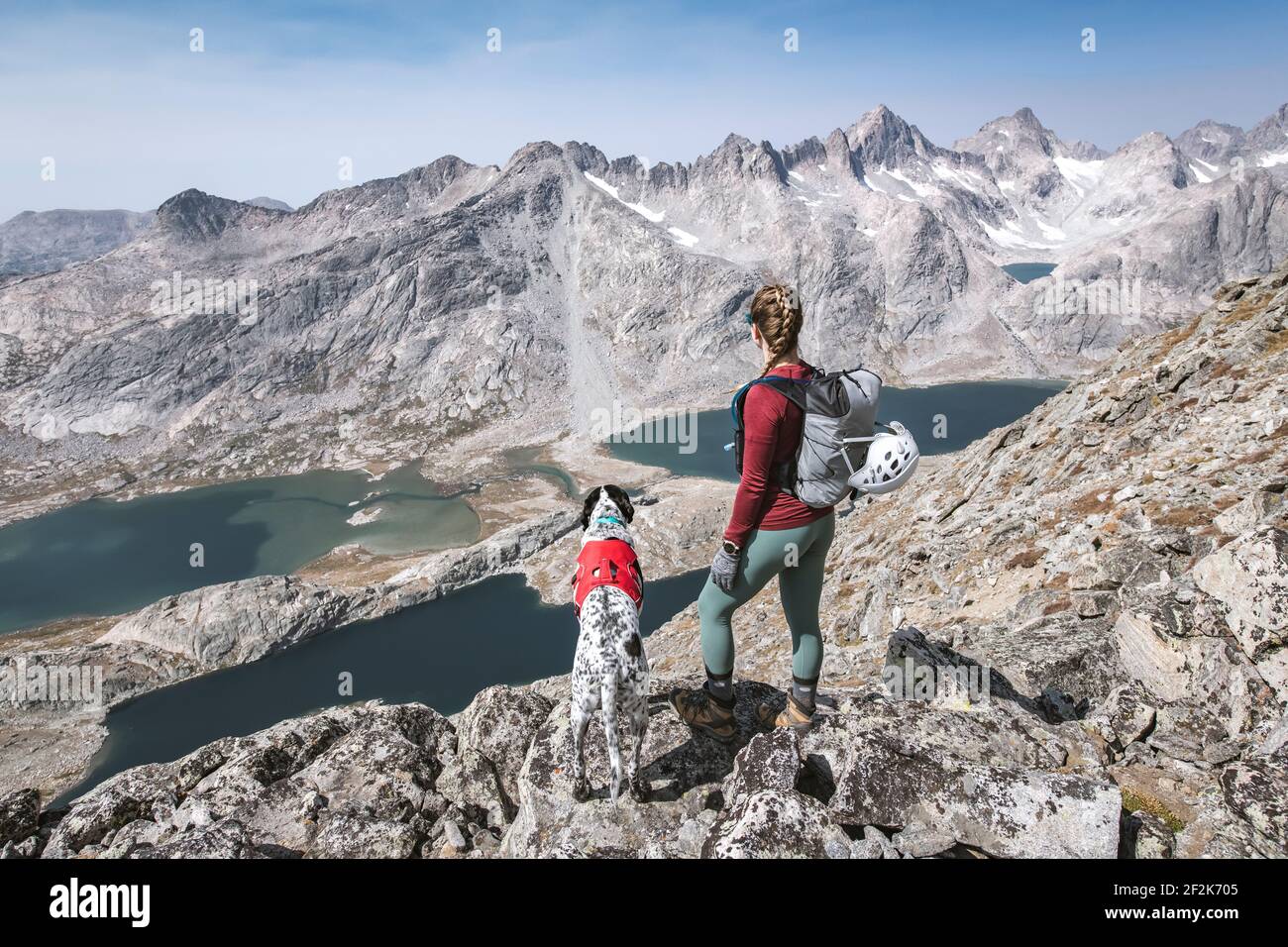 Young woman hiking with dog on mountain during vacation Stock Photo