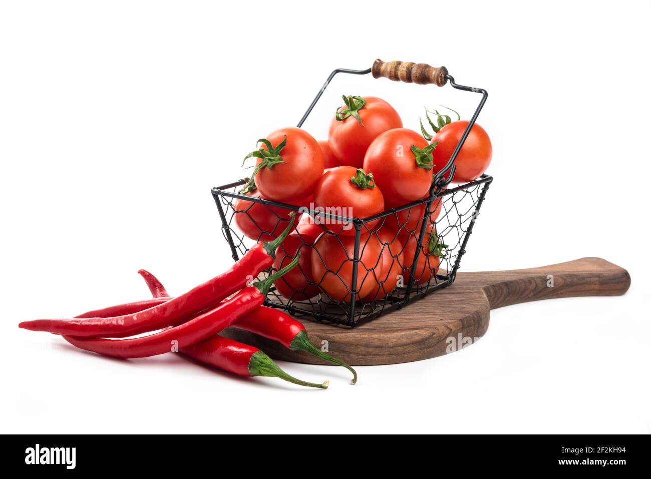 A metallic black basket bowl full of fresh red juicy tomatoes Stock Photo