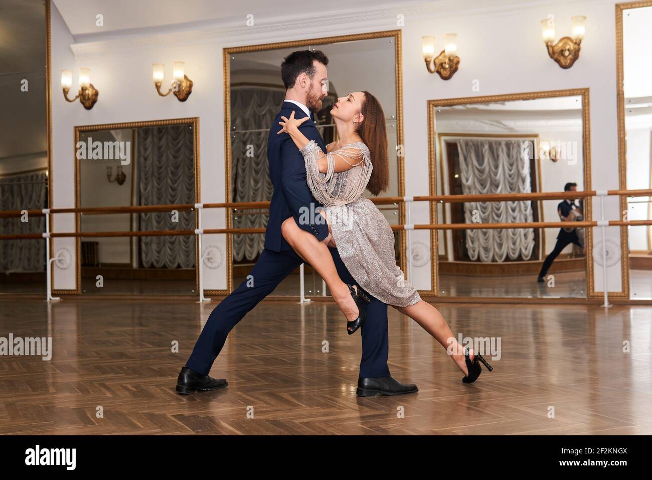 couple practicing to dance tango in a spacious empty hall, reflected in the mirror Stock Photo
