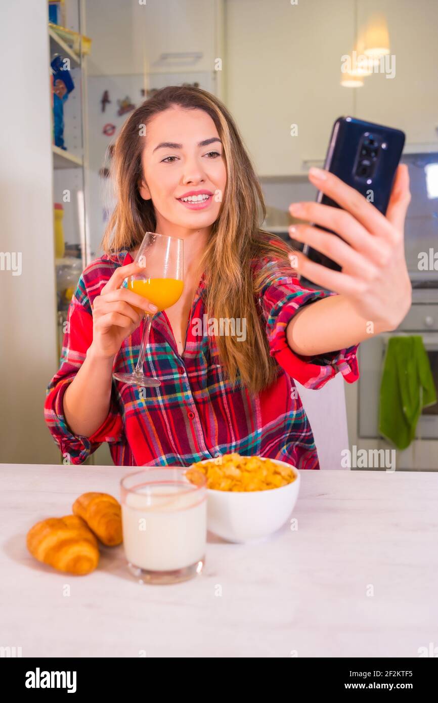 A Spanish blonde woman drinking orange juice and doing a selfie Stock