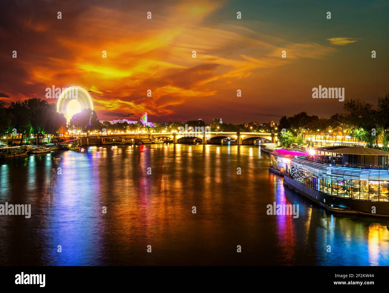 Illuminated ferris wheel and river Seine in Paris at sunset, France Stock Photo