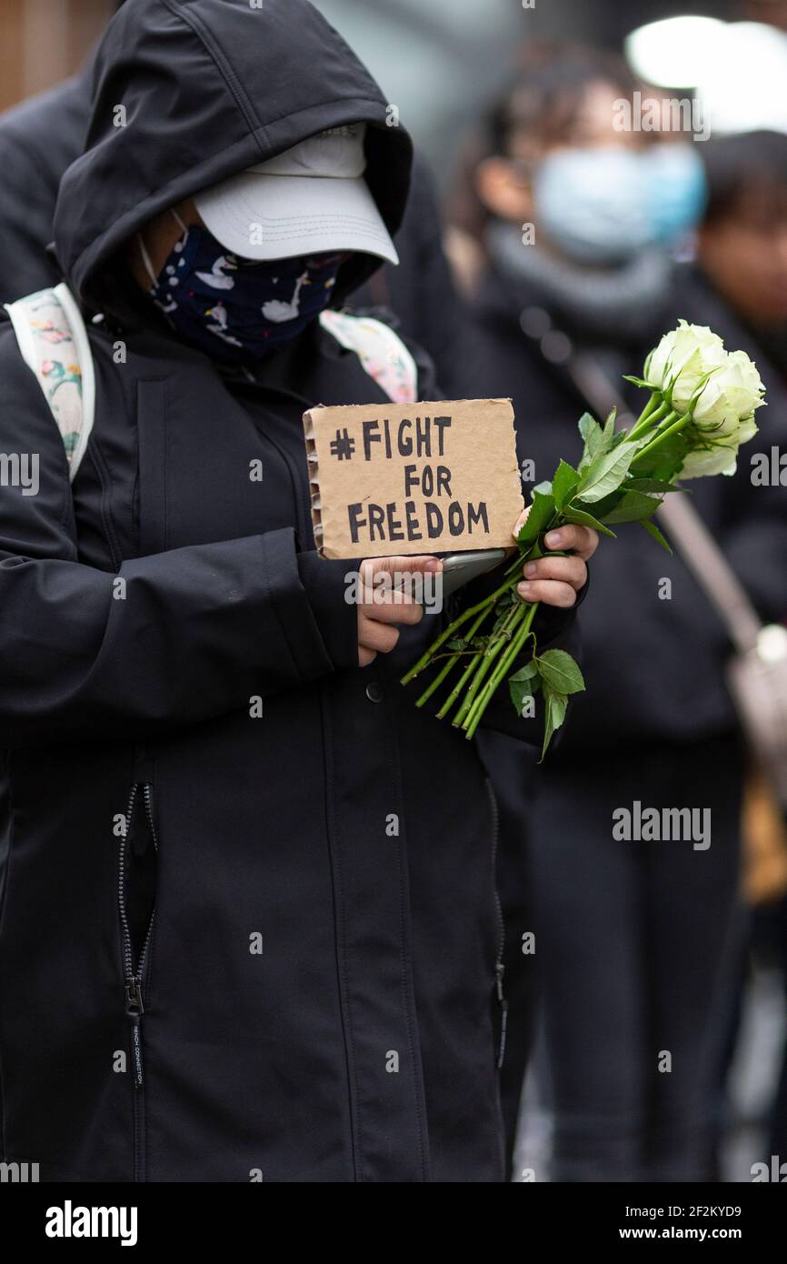 Protester with placard and flowers at demonstration against the Communist Party of China, Leicester Square, London, 12 December 2020 Stock Photo