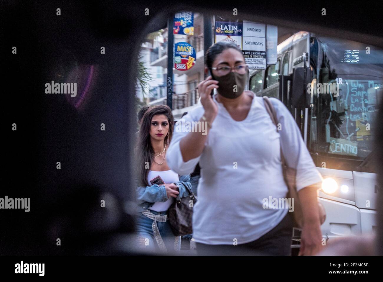 Two women, one with a mask and one without a mask, walk on a street in Mexico Stock Photo