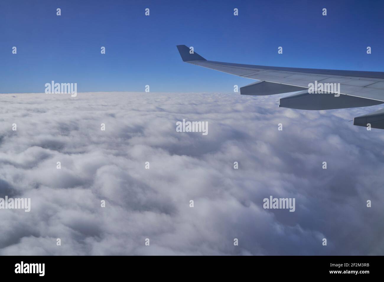 Wing of Airplane Jet above the clouds with blue sky and cloud cover, Atlantic Ocean, Stock Photo