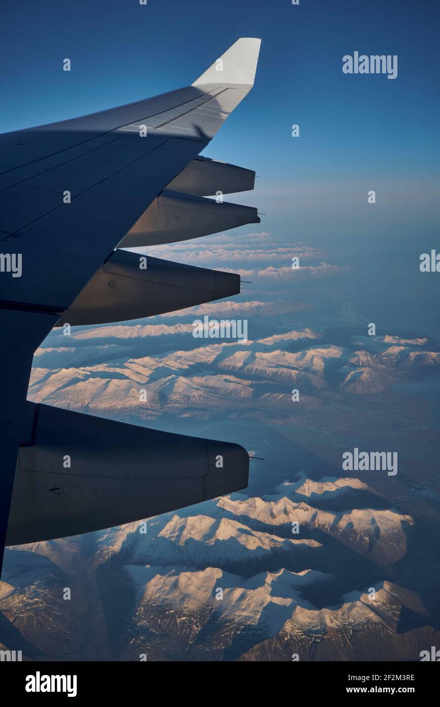 Wing of Airplane Jet above Iceland with mountains and atlantic ocean with blue sky, Iceland, Europe, Stock Photo