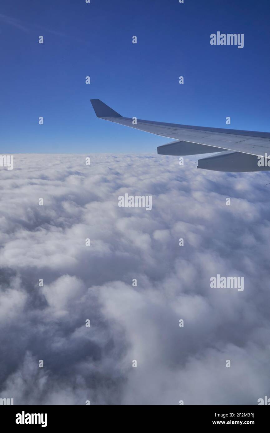 Wing of Airplane Jet above the clouds with blue sky and cloud cover, Atlantic Ocean, Stock Photo