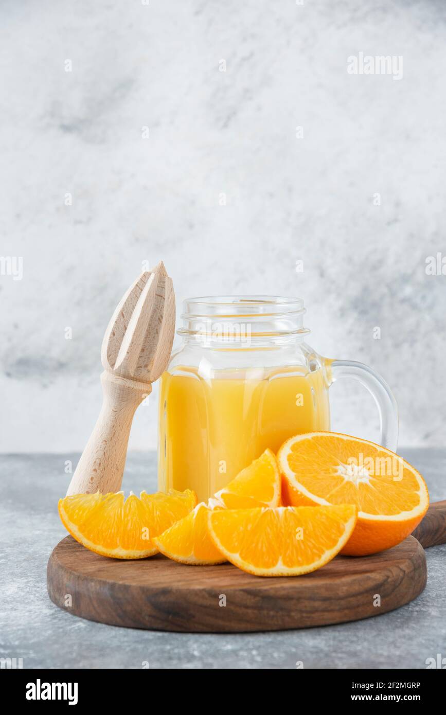 A glass pitcher of juice with fresh orange fruits on stone background Stock Photo