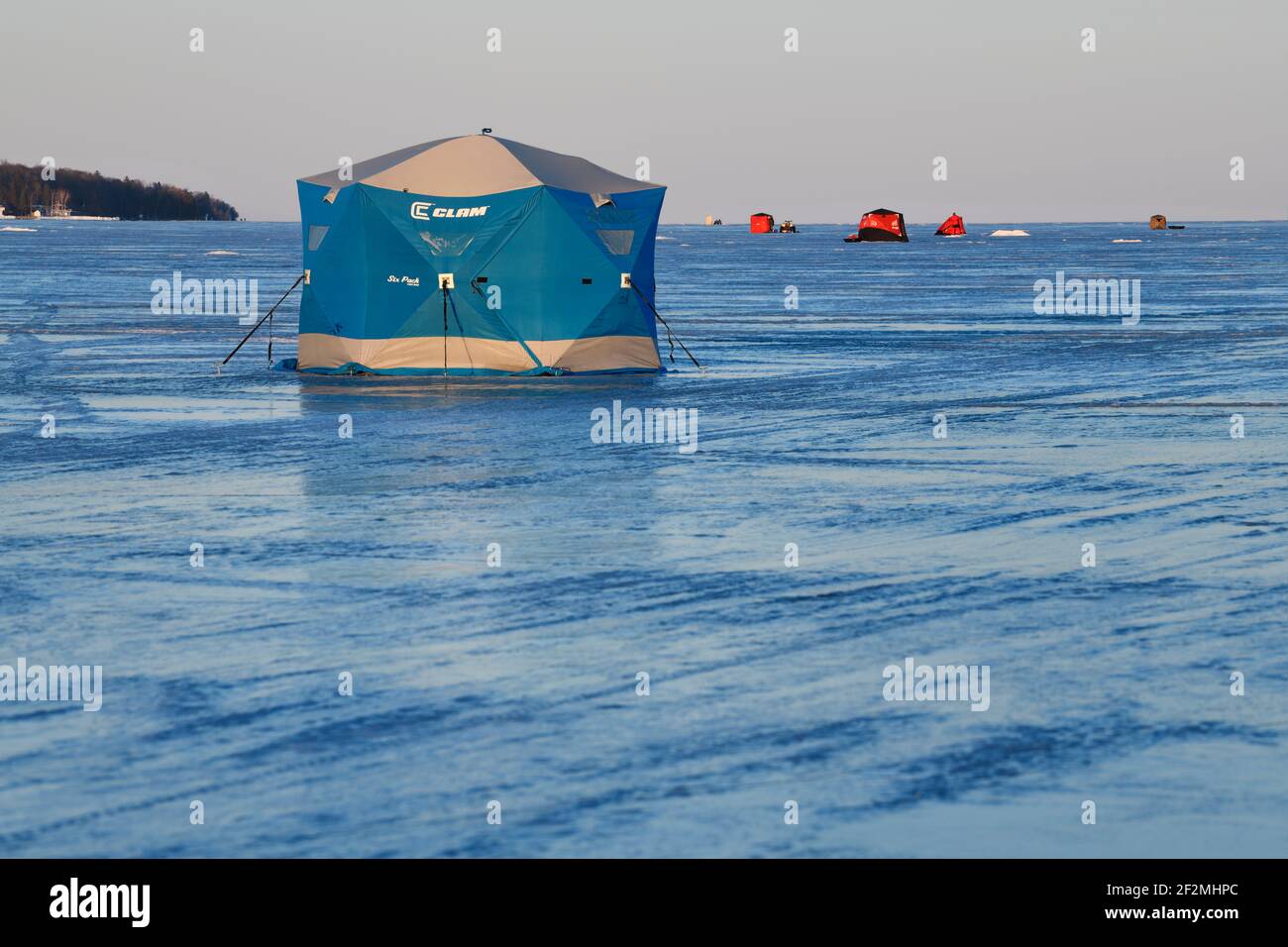 Blue ice fishing tent on frozen Kempenfelt Bay of Lake Simcoe in winter at sunset Stock Photo