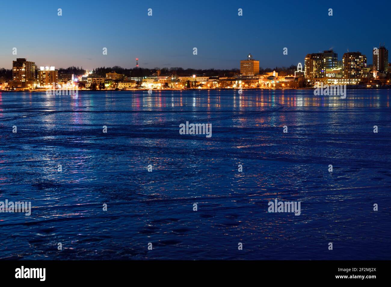 Downtown city lights of Barrie Canada reflected on ice of frozen Kempenfelt Bay Lake Simcoe at twilight on a cold winter night Stock Photo