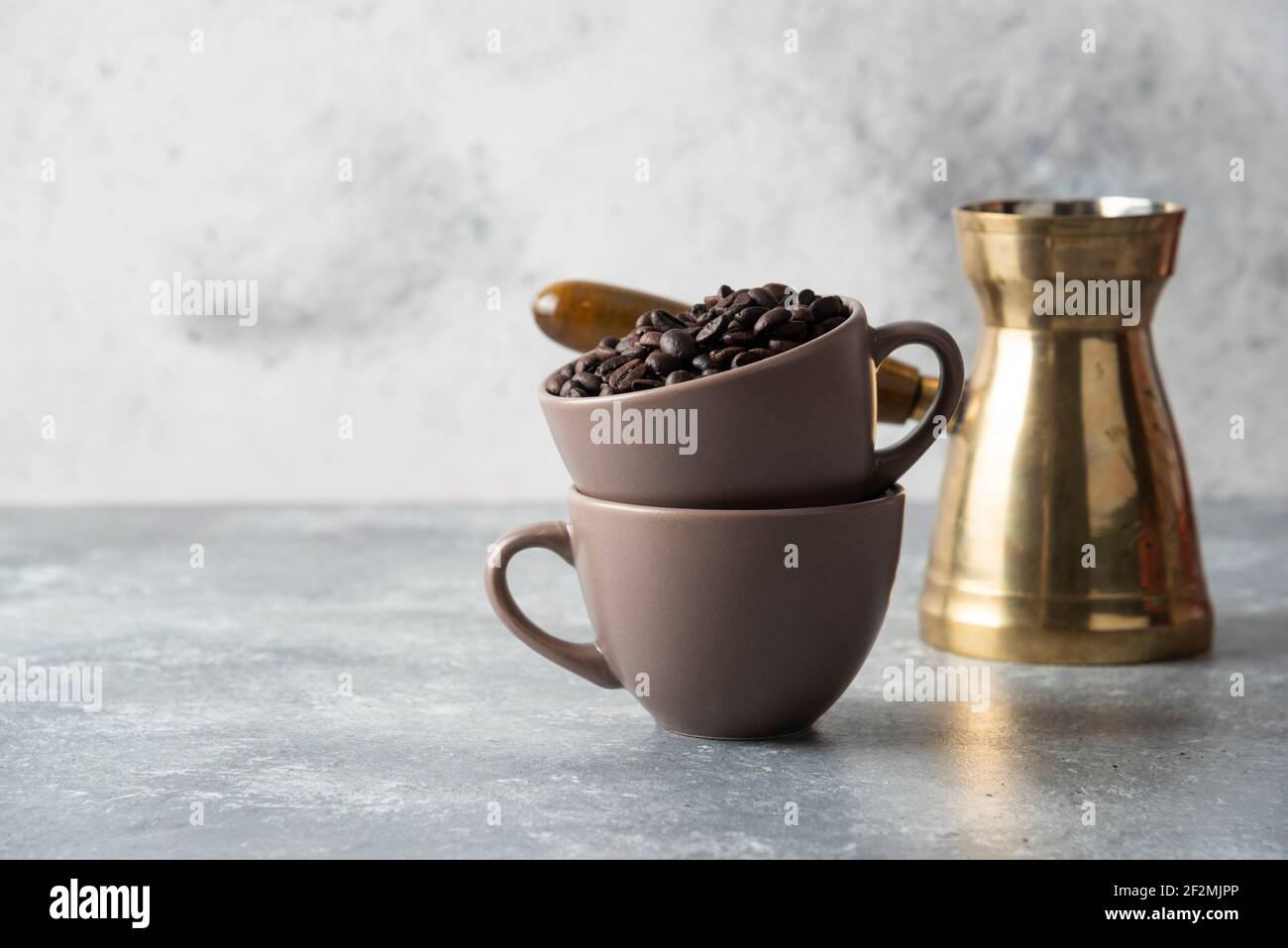 Cup full of coffee beans and coffee maker on marble background Stock Photo