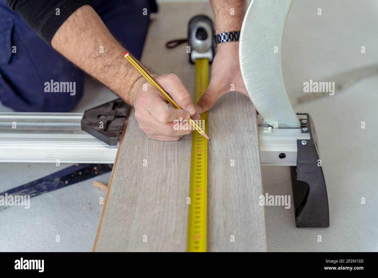 close up of carpenter measuring a wood laminate to lay a wooden decking floor Stock Photo