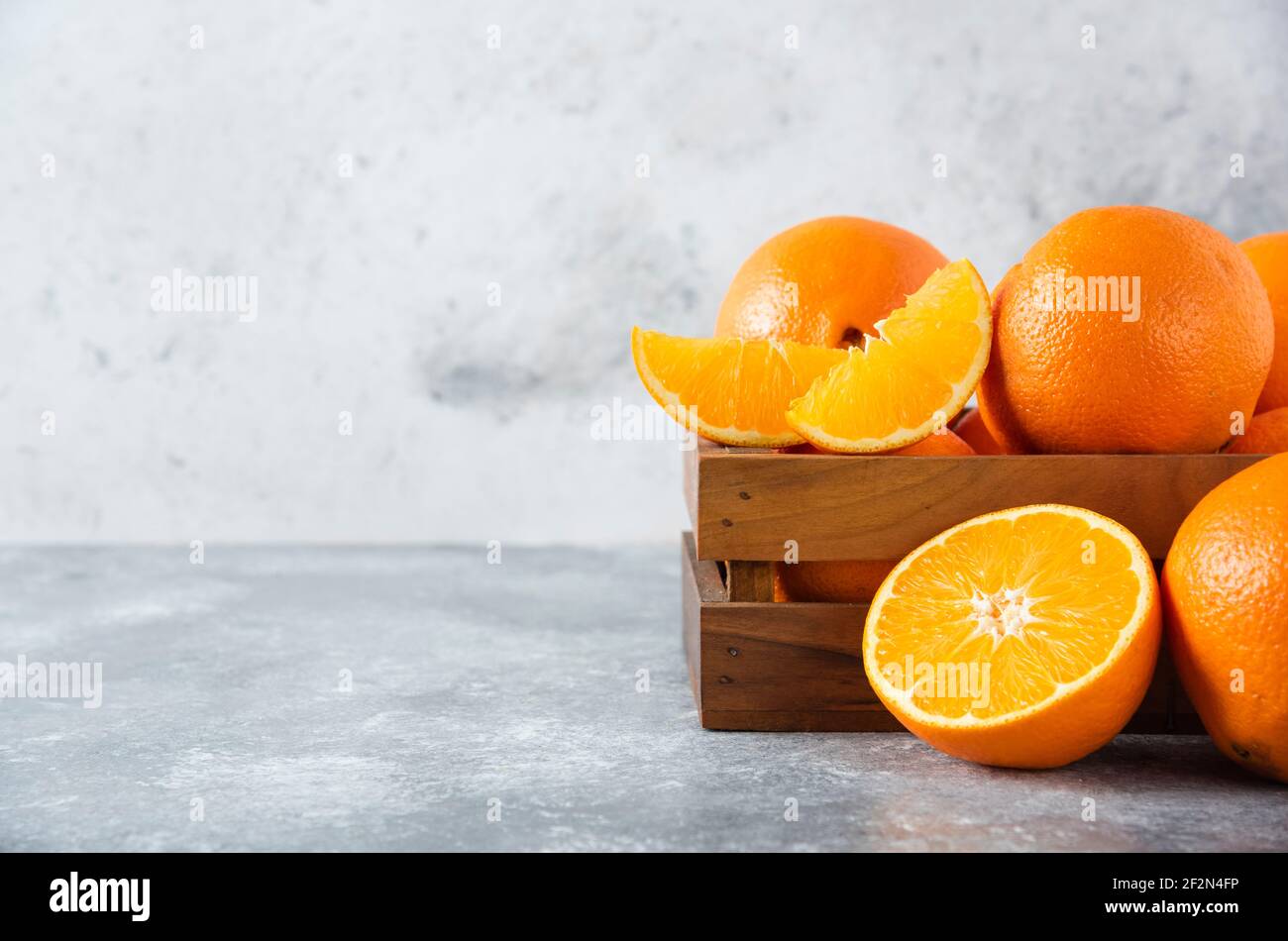 A wooden old box full of juicy orange fruit on stone background Stock Photo