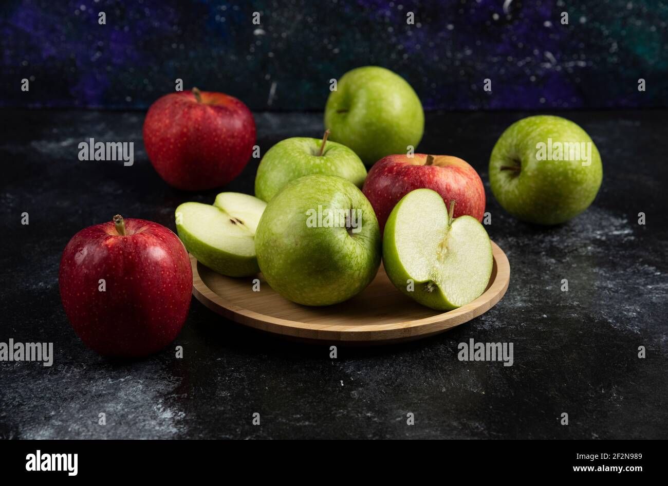 Whole and sliced green and red apples on wooden plate Stock Photo