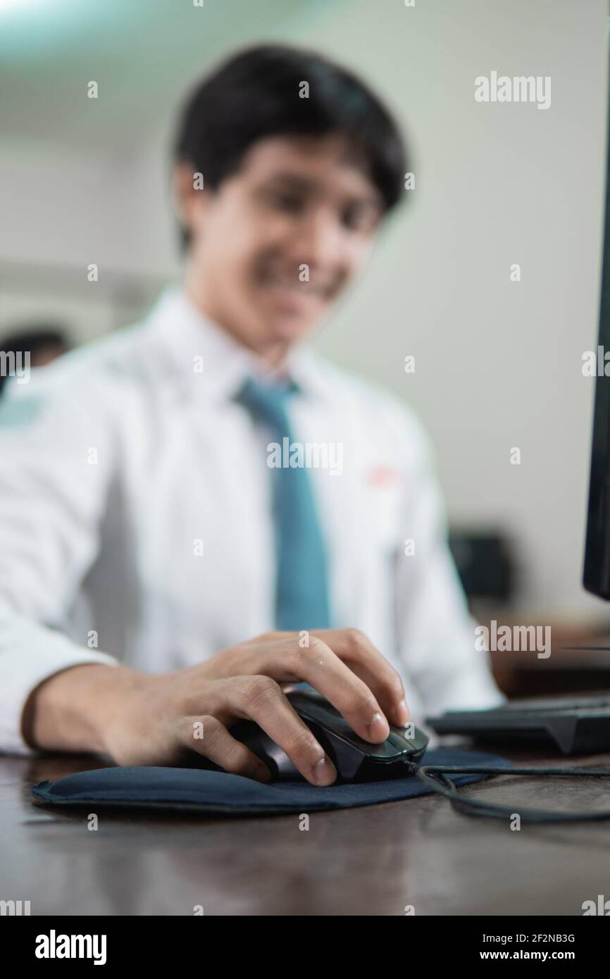 close up of a male student's hand sitting holding a computer mouse while studying Stock Photo