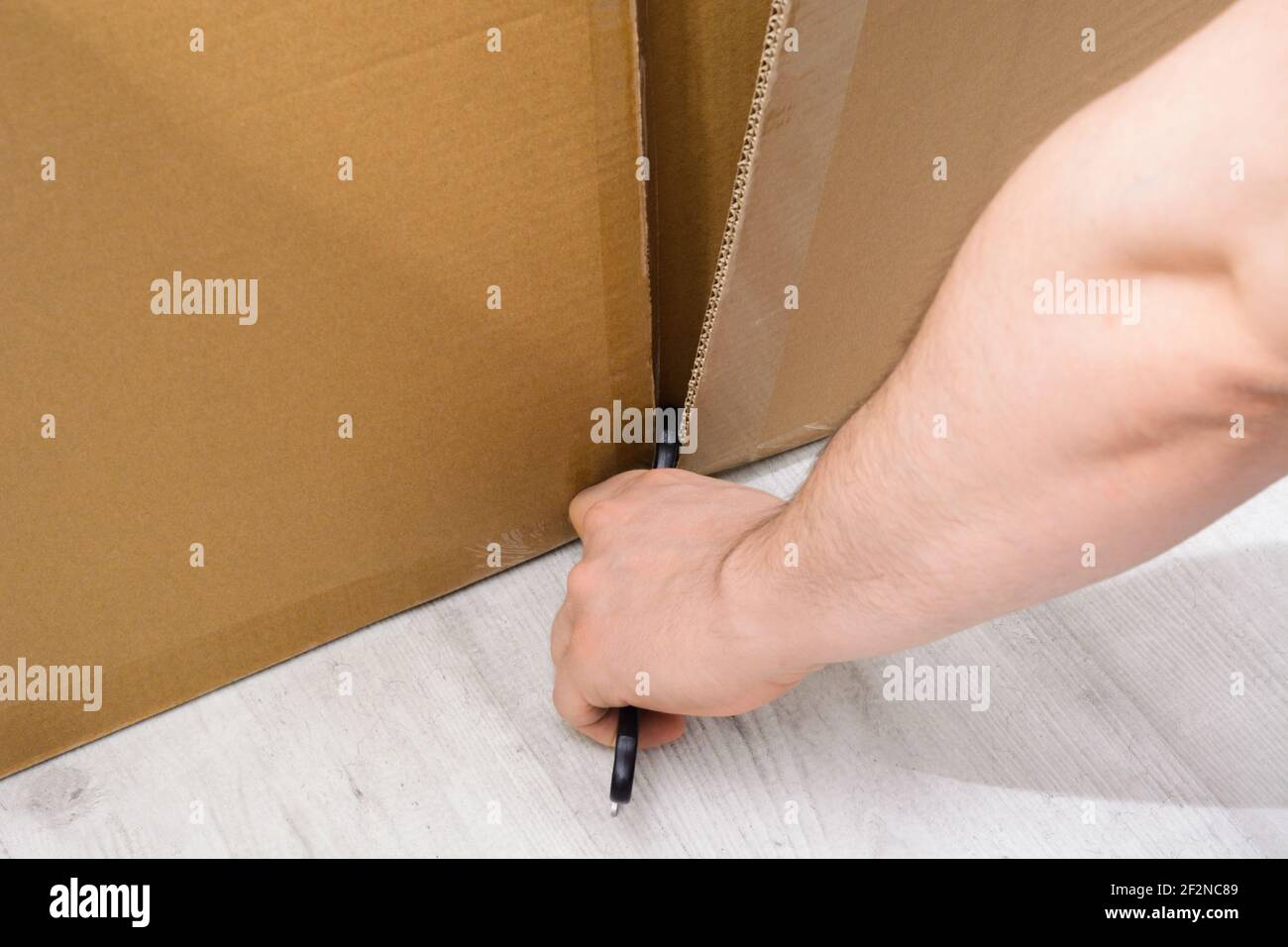 Caucasian man hand cutting a cardboard box with sharp cutter knife