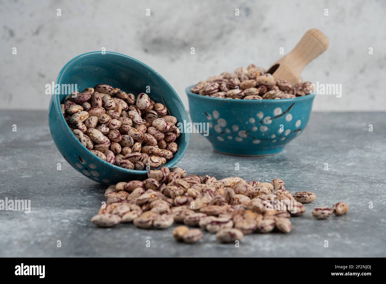 Raw bean grains displayed in bowls on marble surface Stock Photo
