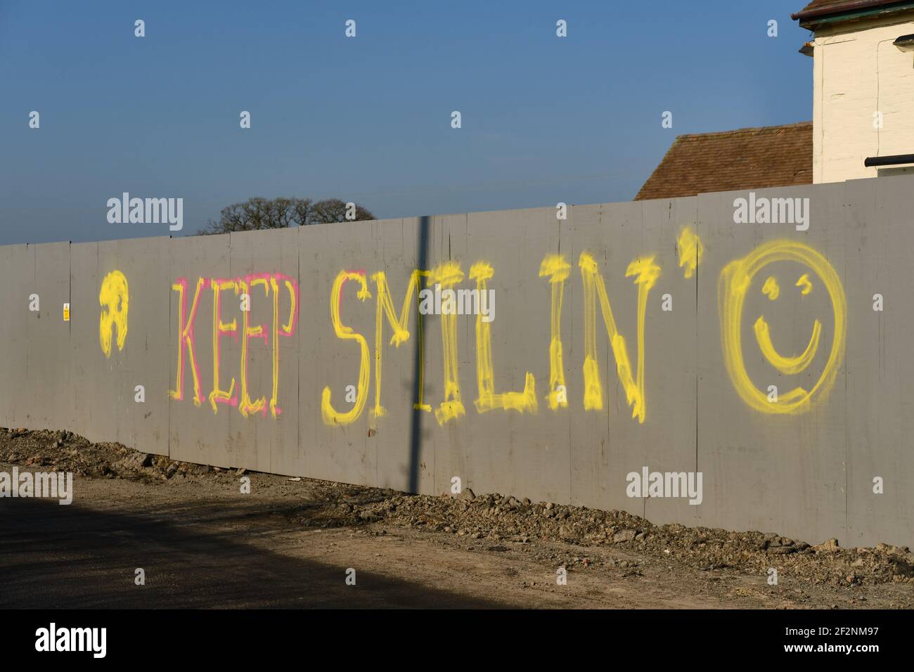 'keep smiling' graffiti on a building-site hoarding in the UK Stock Photo