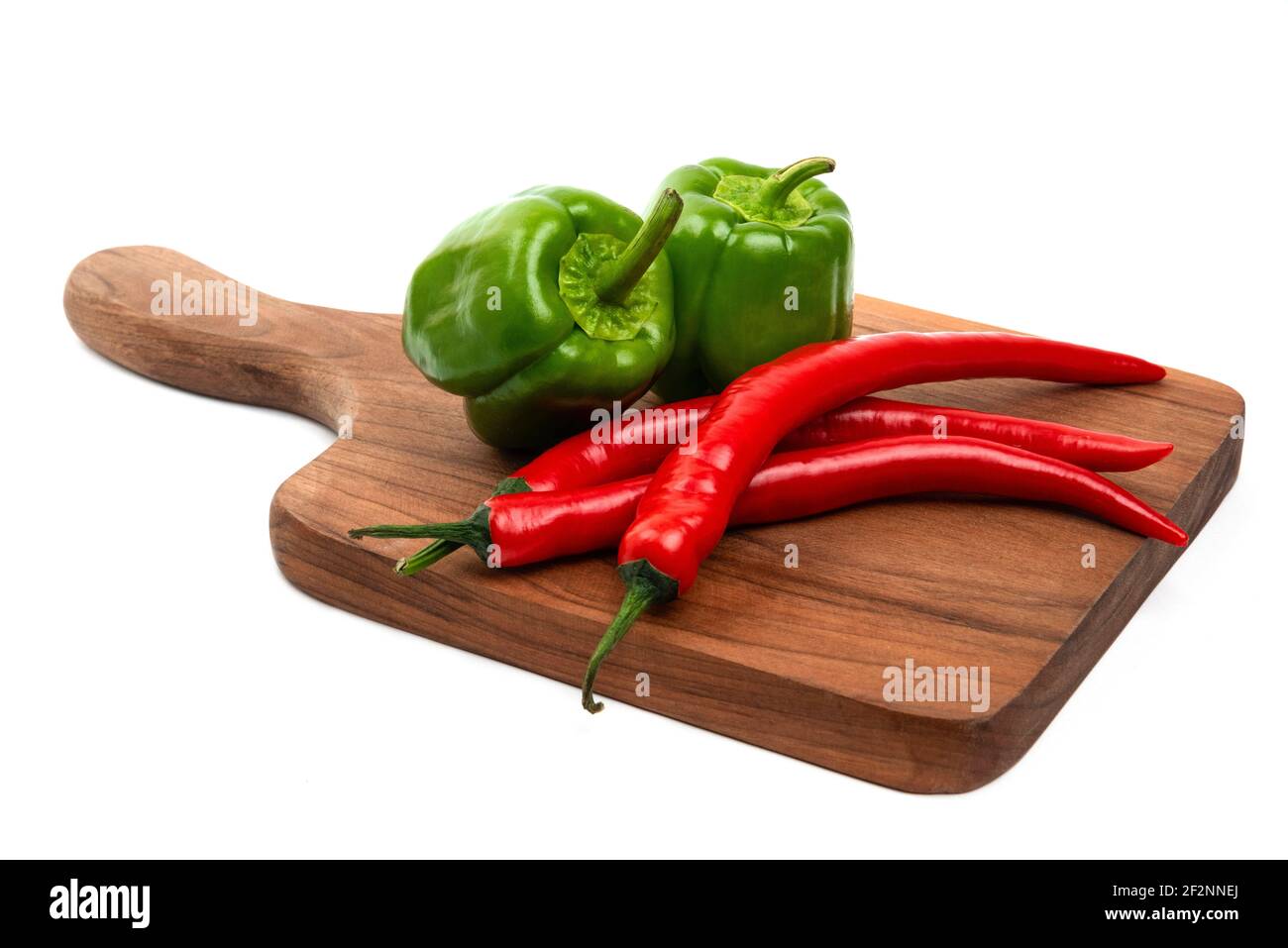 Wooden board of green bell and red chili peppers isolated on white ...