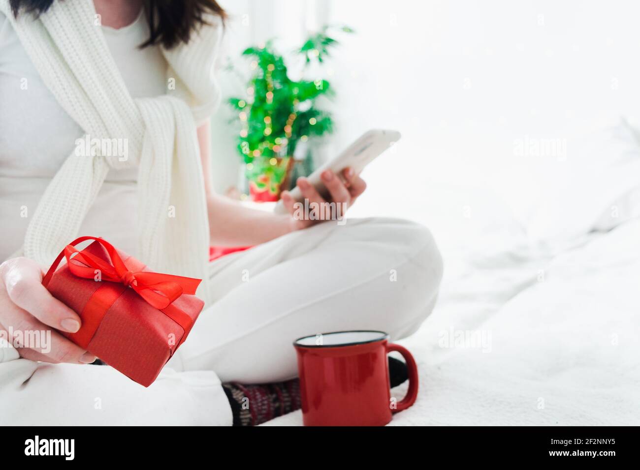 Online shopping concept for holiday with woman, red gift box and phone in hands Stock Photo