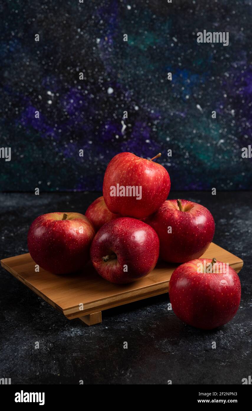 Red whole apples on wooden board on dark background Stock Photo